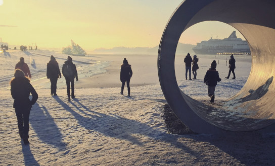 Vinterdag ved havna i Oslo, mennesker i motlys og snø og lange skygger
